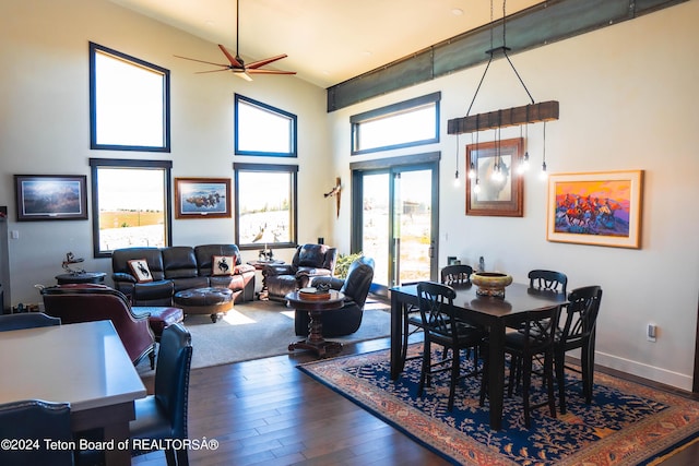 dining room with ceiling fan, dark hardwood / wood-style floors, and a towering ceiling