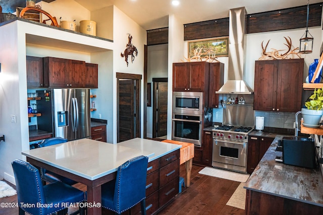 kitchen featuring pendant lighting, appliances with stainless steel finishes, a center island, backsplash, and dark hardwood / wood-style floors