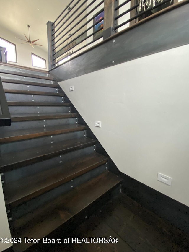 stairway featuring a high ceiling and wood-type flooring