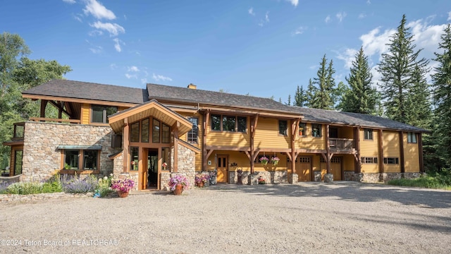 155 E Buck Mountain Rd, Jackson, WY 83001 - view of front of house featuring a chimney, stone siding, and roof with shingles