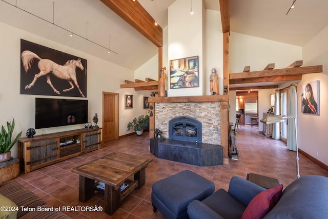 living room featuring beam ceiling, dark tile patterned flooring, a stone fireplace, and track lighting