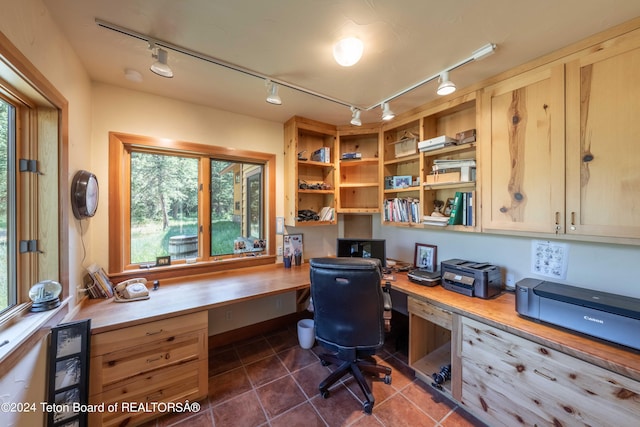 tiled office space featuring a wealth of natural light, track lighting, and built in desk