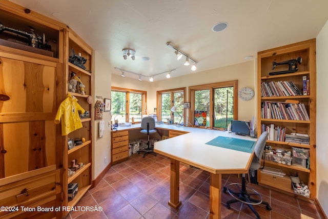 home office with dark tile patterned floors and track lighting