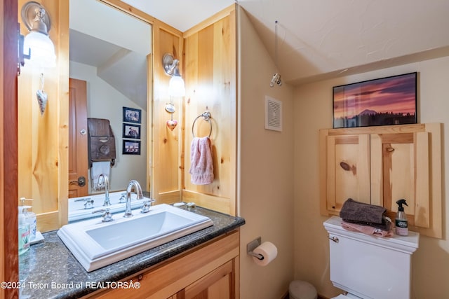 bathroom with vaulted ceiling, vanity, and toilet