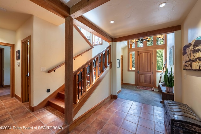 tiled entrance foyer featuring beamed ceiling