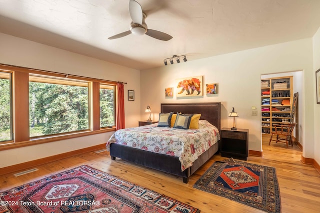 bedroom with light hardwood / wood-style flooring, ceiling fan, and rail lighting