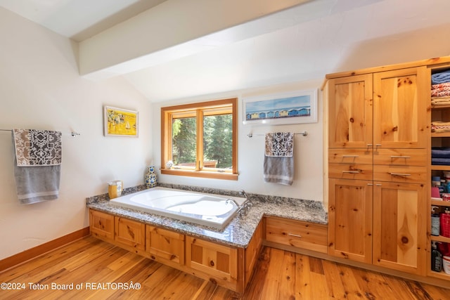 bathroom with a tub, hardwood / wood-style floors, and lofted ceiling with beams