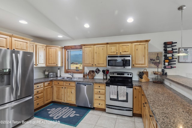 kitchen featuring light tile patterned flooring, lofted ceiling, stainless steel appliances, pendant lighting, and sink