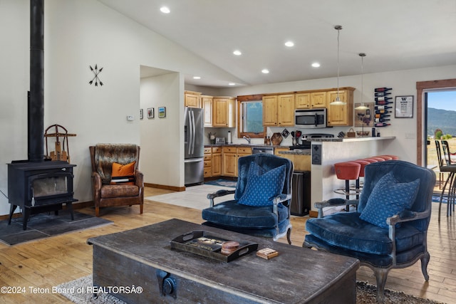 living room featuring sink, light wood-type flooring, lofted ceiling, and a wood stove