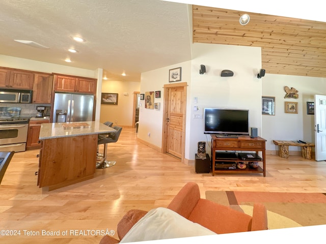 kitchen with a kitchen island, a breakfast bar, stainless steel appliances, light stone countertops, and light hardwood / wood-style flooring