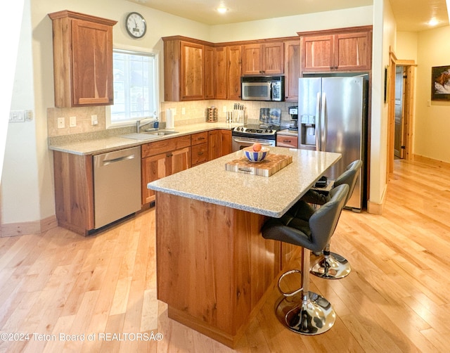 kitchen with stainless steel appliances, a kitchen island, backsplash, and light wood-type flooring