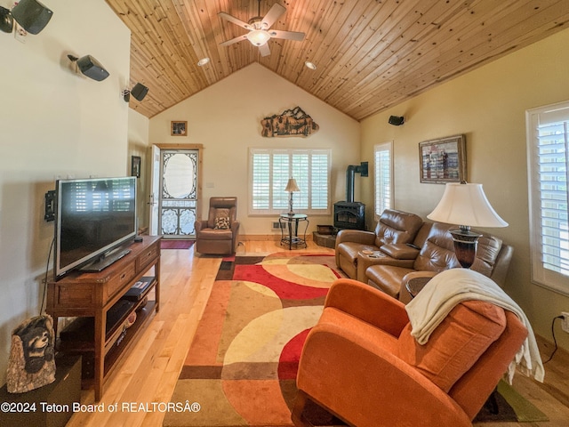 living room with wood ceiling, ceiling fan, high vaulted ceiling, light hardwood / wood-style floors, and a wood stove