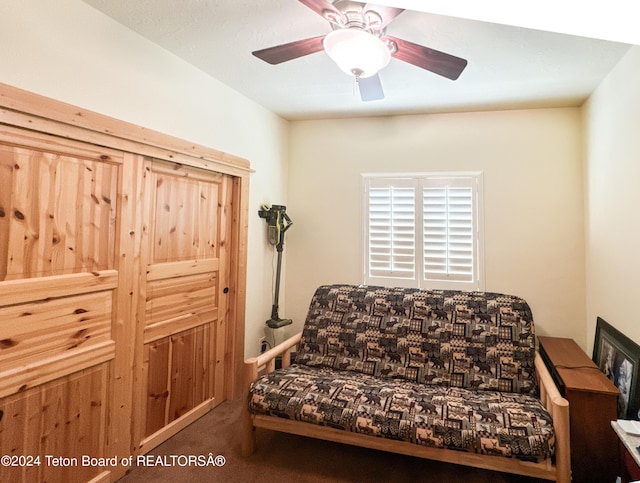 sitting room featuring dark colored carpet and ceiling fan