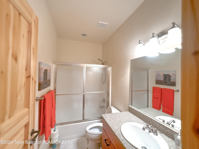 full bathroom featuring toilet, tile patterned floors, vanity, and bath / shower combo with glass door