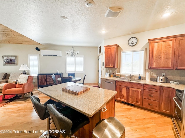 kitchen with a kitchen island, decorative light fixtures, sink, a wall mounted AC, and stainless steel appliances