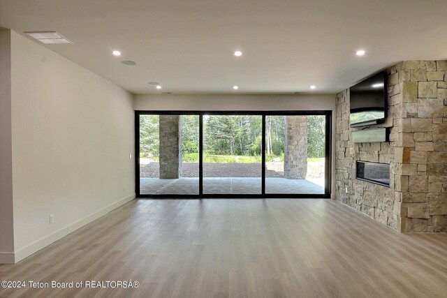 unfurnished living room featuring a healthy amount of sunlight, a fireplace, and light hardwood / wood-style flooring