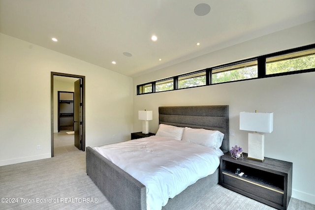 bedroom featuring vaulted ceiling, light colored carpet, and a spacious closet