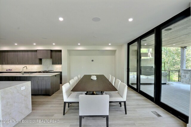 dining space featuring light wood-type flooring, sink, and floor to ceiling windows