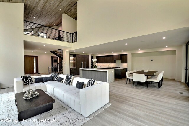 living room with a towering ceiling, wood ceiling, and light hardwood / wood-style floors