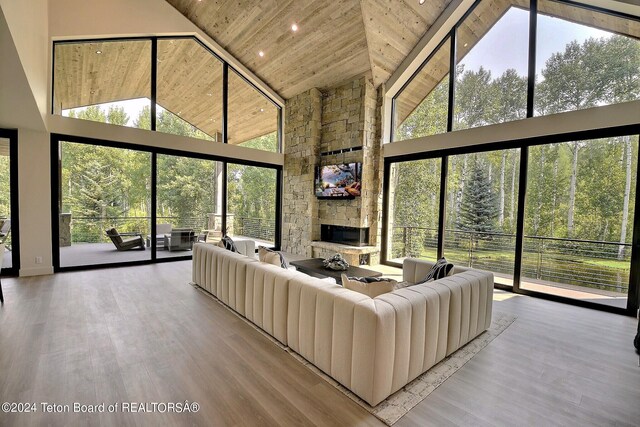 unfurnished living room featuring light wood-type flooring, wood ceiling, a stone fireplace, and high vaulted ceiling