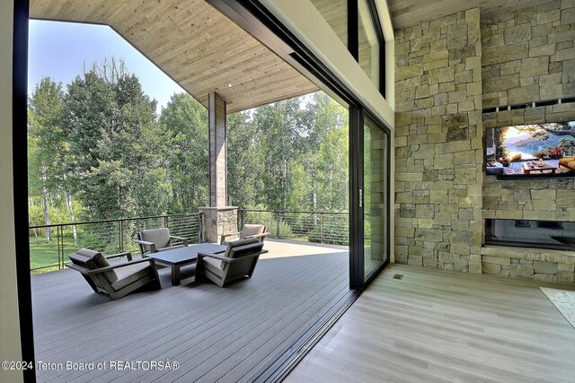 wooden terrace with an outdoor living space with a fireplace