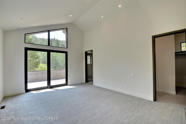 unfurnished living room with light carpet and high vaulted ceiling