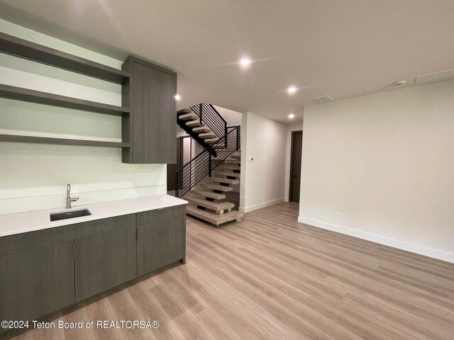 interior space with light wood-type flooring, dark brown cabinetry, and sink