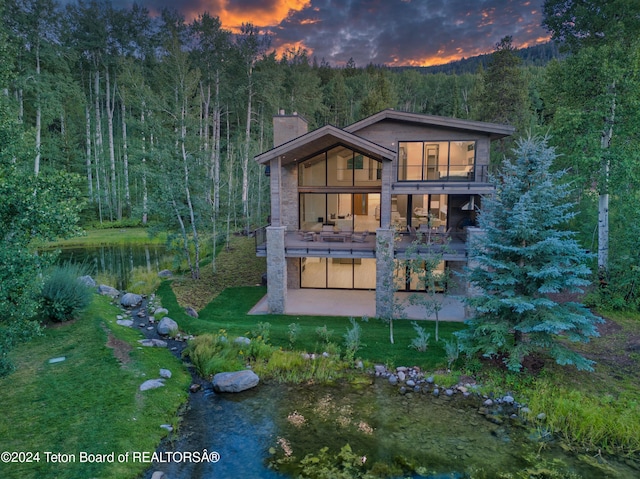 6 Blackfoot Trl, Victor, ID 83455 - back of house with a wooded view, a lawn, a chimney, a balcony, and a patio