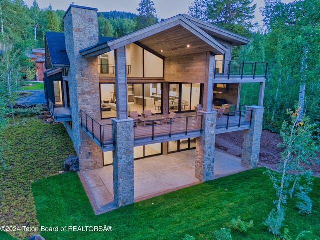 rear view of property featuring a lawn, outdoor lounge area, a balcony, and a patio