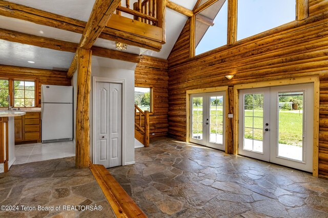 interior space featuring high vaulted ceiling, white refrigerator, beamed ceiling, french doors, and rustic walls