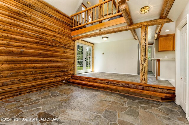 interior space with log walls, a towering ceiling, and french doors