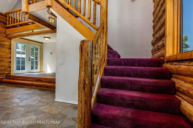 stairway featuring tile patterned flooring, french doors, and rustic walls