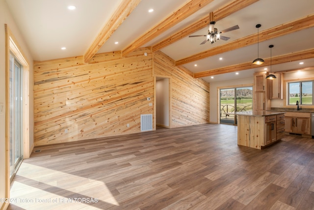 interior space with wood walls, ceiling fan, hardwood / wood-style floors, and beam ceiling