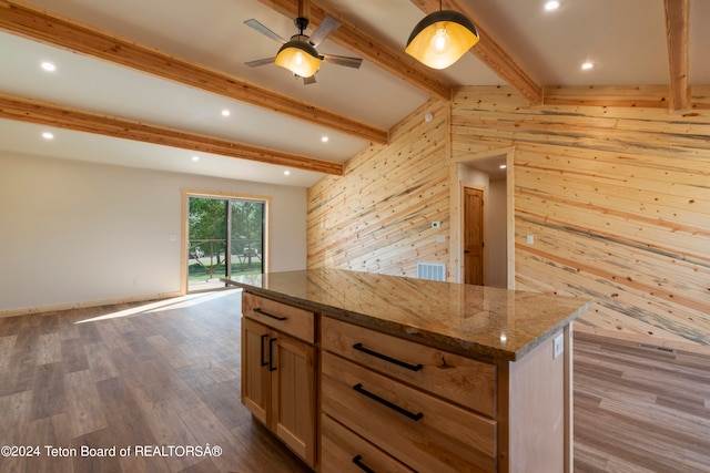 kitchen with wooden walls, stone countertops, beam ceiling, ceiling fan, and wood-type flooring