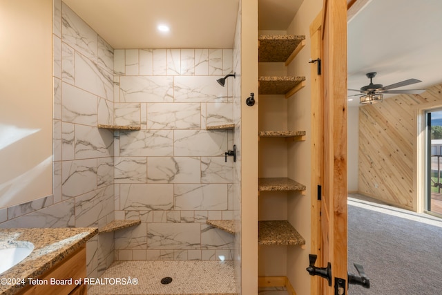 bathroom with tiled shower, vanity, and ceiling fan