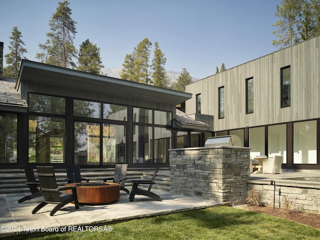 7750 N Lower Granite Ridge Rd, Teton Village, WY 83025 - rear view of property with a fire pit, a patio area, and a sunroom