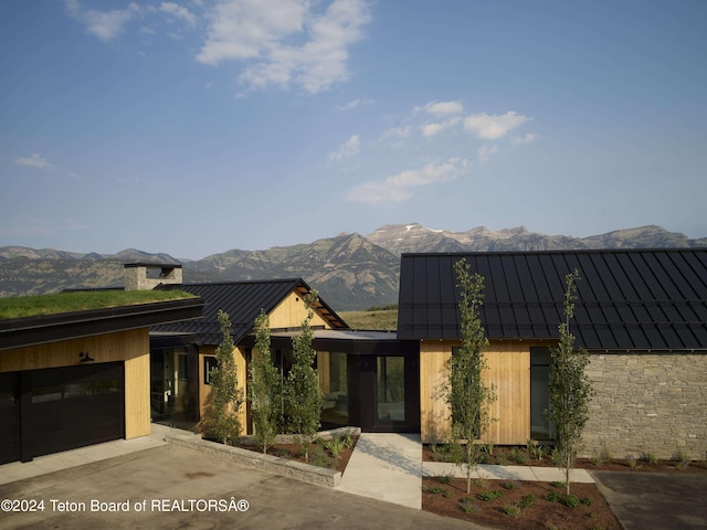 2680 Trader Rd, Jackson, WY 83001 - view of front of property featuring stone siding, a mountain view, metal roof, driveway, and a standing seam roof