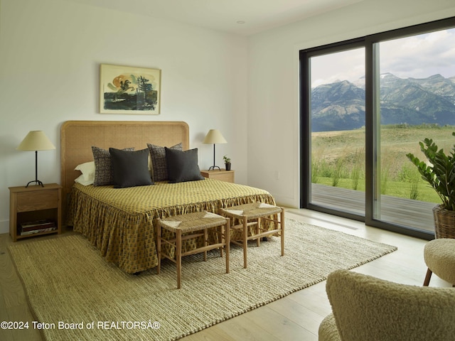 bedroom with a mountain view, access to outside, and light hardwood / wood-style flooring