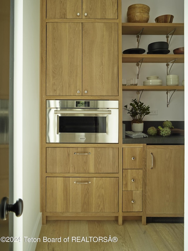 kitchen with light hardwood / wood-style flooring and stainless steel oven