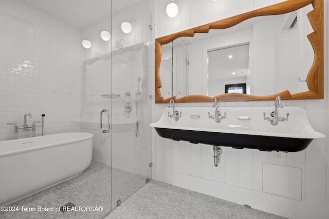 bathroom featuring decorative backsplash, tile walls, a shower with shower door, and sink