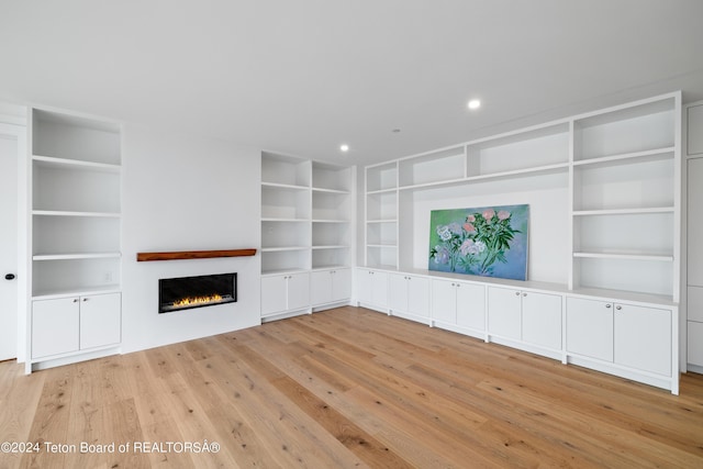 2680 Trader Rd, Jackson, WY 83001 - unfurnished living room with a warm lit fireplace, recessed lighting, light wood-type flooring, and built in shelves
