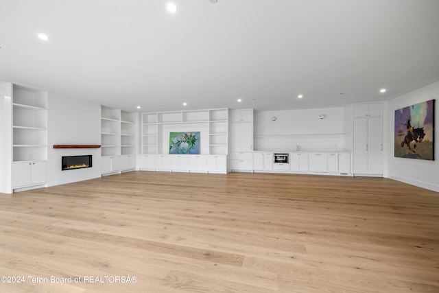 unfurnished living room with built in features and light wood-type flooring