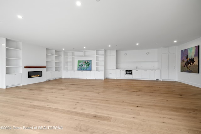 2680 Trader Rd, Jackson, WY 83001 - unfurnished living room with built in features, light wood-style flooring, a glass covered fireplace, and recessed lighting