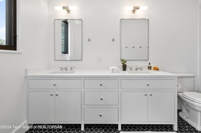 bathroom featuring tile patterned floors, toilet, and dual bowl vanity