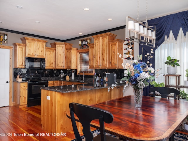 kitchen with pendant lighting, crown molding, black appliances, kitchen peninsula, and dark stone counters