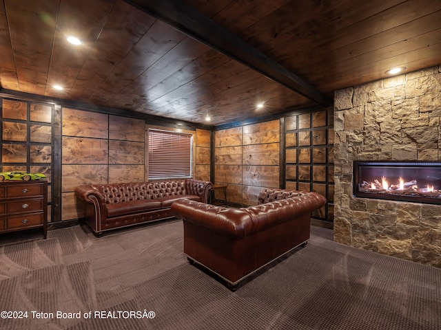 carpeted home theater featuring a fireplace, wood ceiling, wooden walls, and beamed ceiling