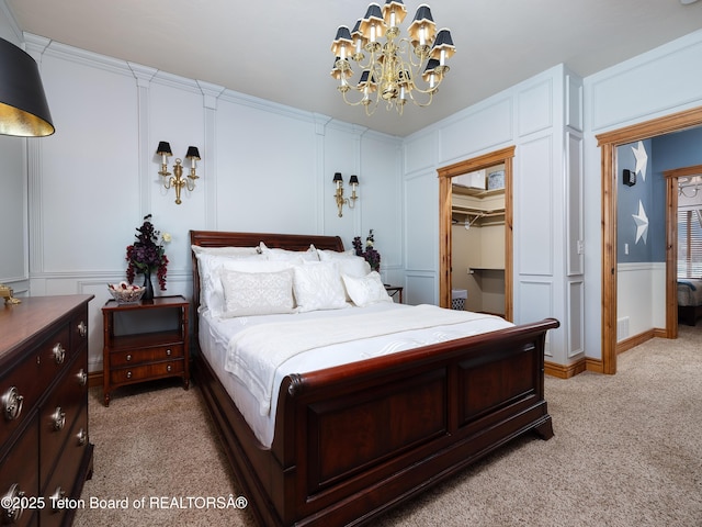 carpeted bedroom featuring ornamental molding, a walk in closet, an inviting chandelier, and a closet