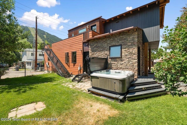 back of property featuring central AC, a hot tub, and a yard