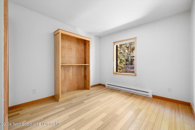 unfurnished bedroom featuring baseboard heating and light hardwood / wood-style flooring