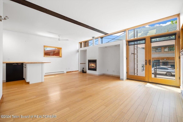 unfurnished living room featuring baseboard heating, ceiling fan, light hardwood / wood-style floors, and beamed ceiling